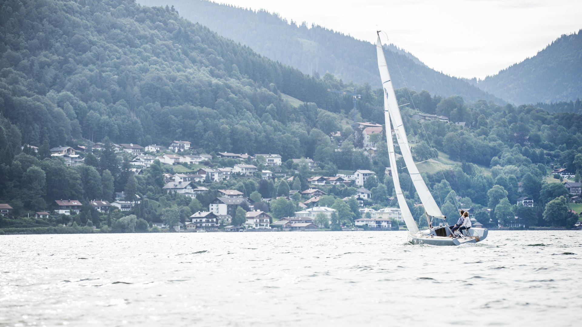 Ein Segelboot segelt auf dem Tegernsee mit Blick auf Stadt Tegernsee., © Hansi Heckmair